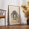 TIGERFIGHT limited edition saber tooth skull art print in wood frame displayed on hardwood floors next to mid-century modern wooden chair and golden palm plant in contemporary living room